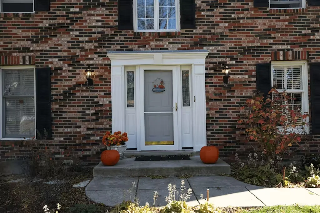 Brick colonial home with a white entry door surround and black shutters