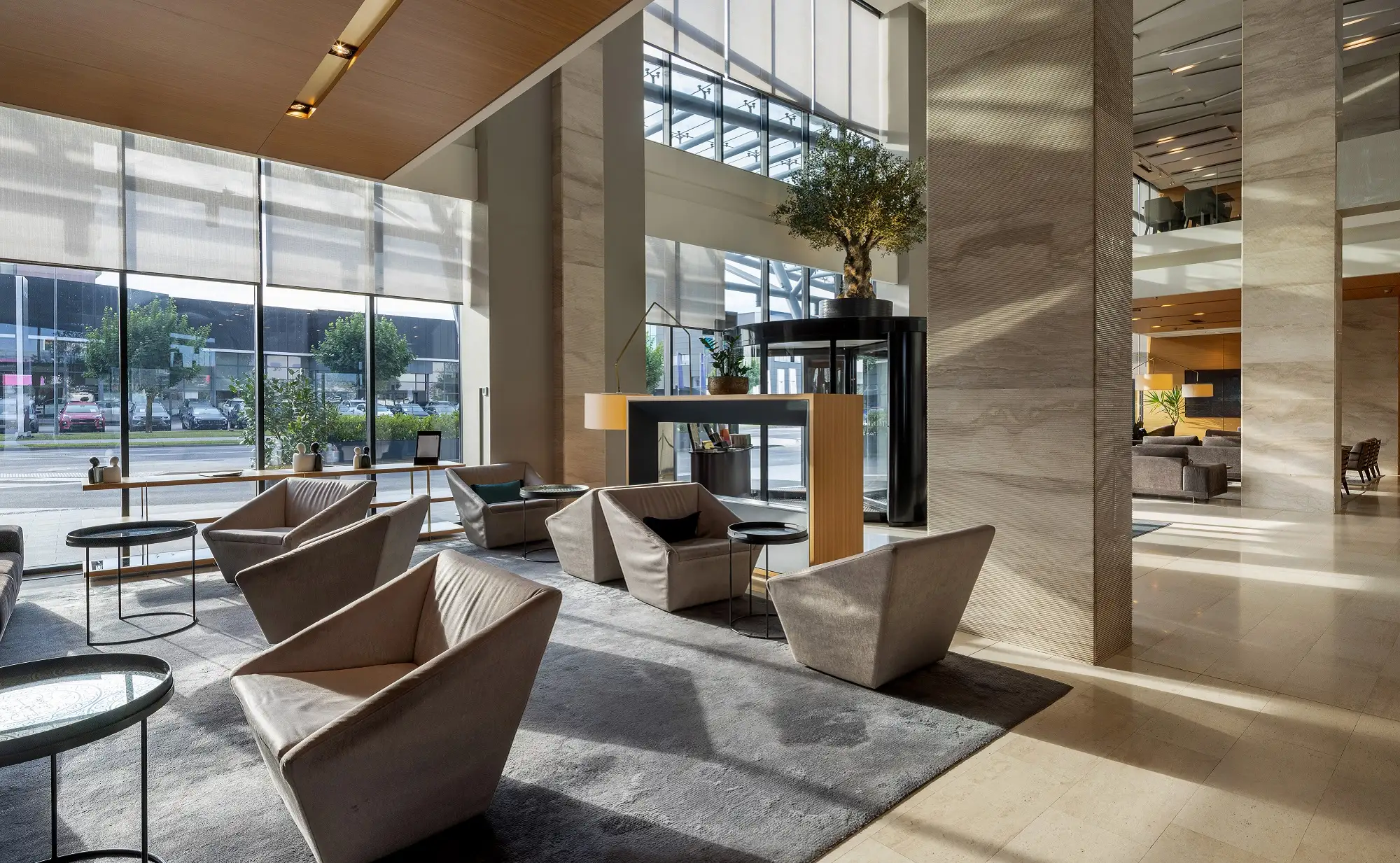 Renovated commercial building lobby with floor-to-ceiling windows, stone-clad columns and lounge seating